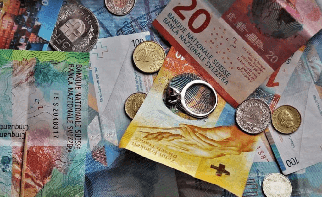 Swiss currency with coins, banknotes, and a ring placed on top.