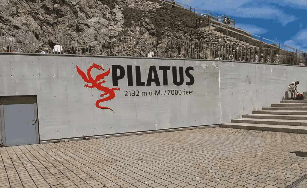 Sign at the summit of Mount Pilatus with the mountain name, dragon logo and elevation of 2132 meters/7000 feet.