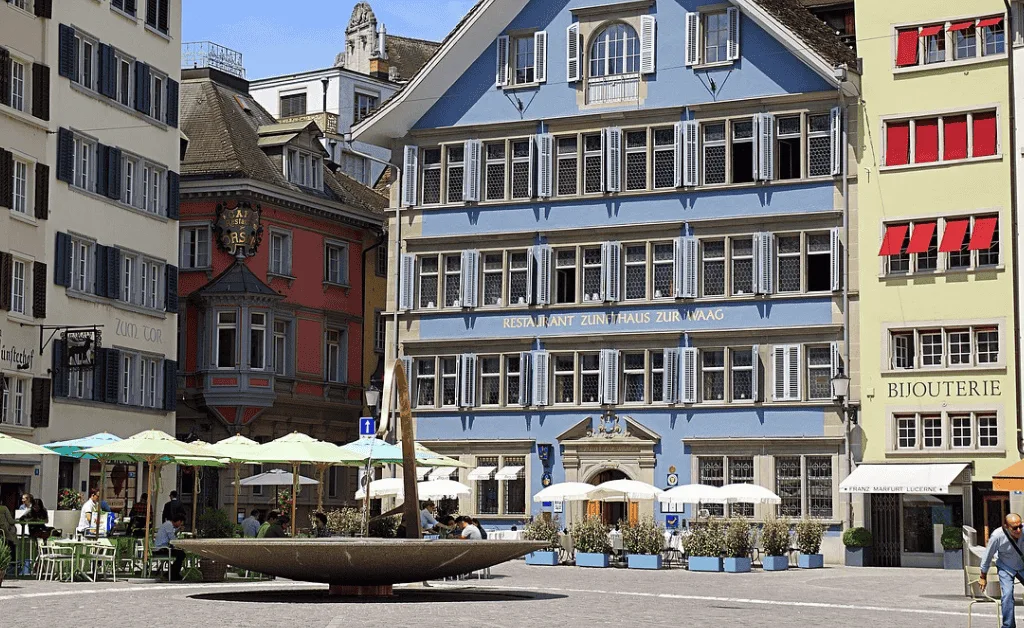 Zurich Old Town square with historic buildings, outdoor seating, and fountain.