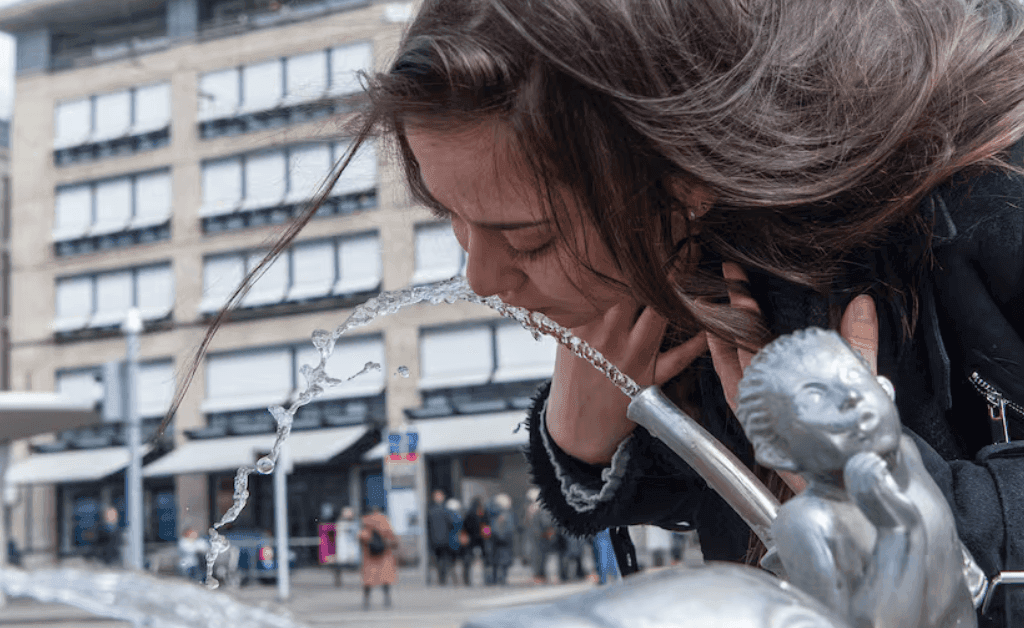Woman drinking from a public water fountain in zurich